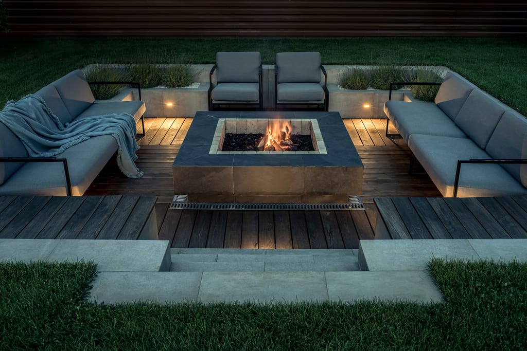 Backayrd in Bonsall, CA with a dark wooden deck, white outdoor furniture, and a fire pit.