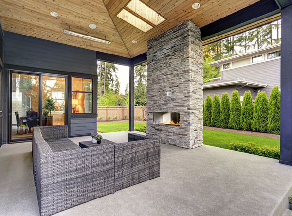 Covered patio with modern fireplace and vaulted ceiling.
