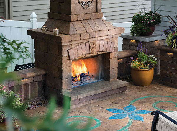 Outdoor fireplace with blue paving stones laid in a flower pattern.