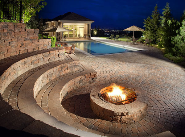 Triple row seating area surrounding a fire pit with a pool close by.