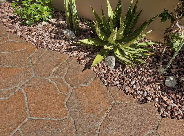 Beautiful red flagstone pavers next to color matching loose rock stones and drought tolerant plants.
