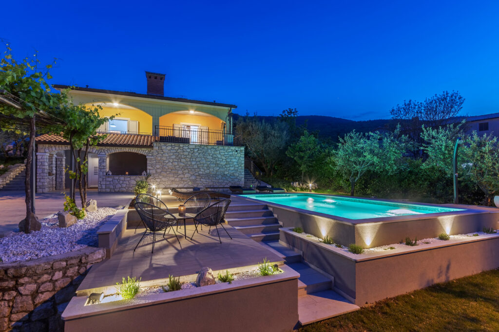 Nighttime view of a pool with modern hardscape landscaping in Lakeside, CA. 