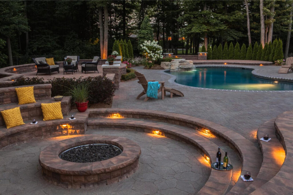 Outdoor hardscaping with landscape lighting and a pool. 