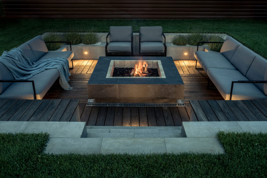 Backayrd in Bonsall, CA with a dark wooden deck, white outdoor furniture, and a fire pit. 