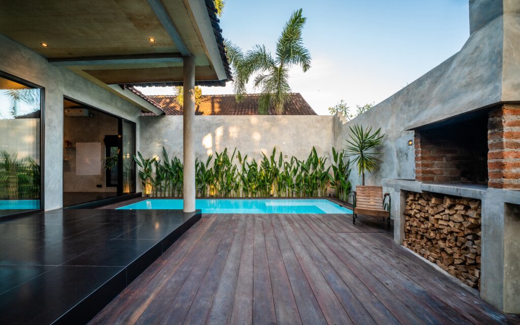 Pool next to a dark wooden deck in a backyard in Bonsall, CA. 