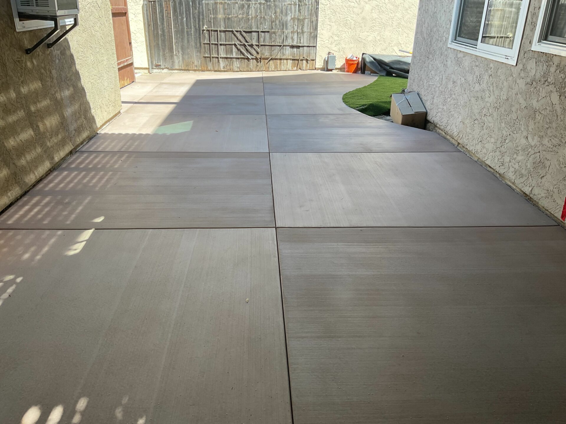 The rebuilt side yard with new control-joint concrete panels and a turf strip tucked against the foundation.