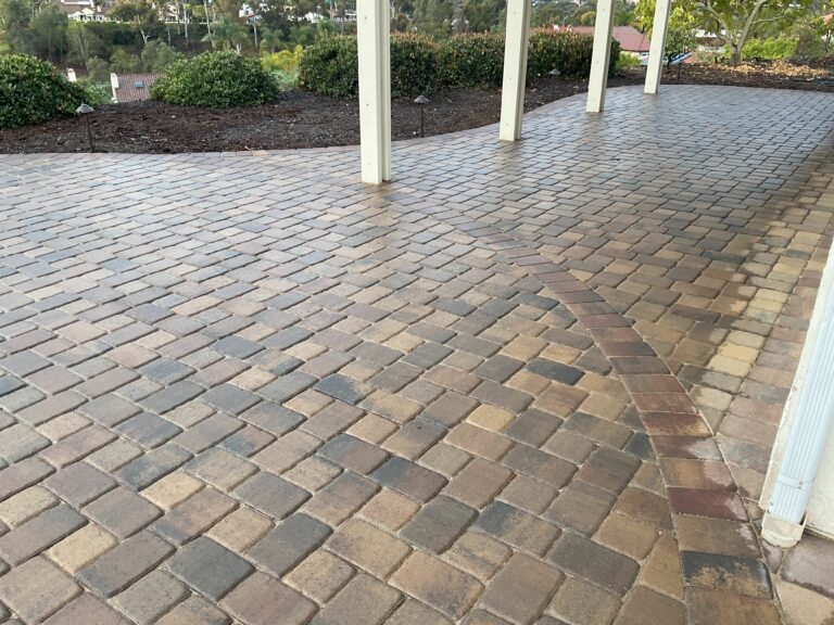 Wet cobble-style brick pavers on a covered patio, showing a curved border pattern between two laying directions.
