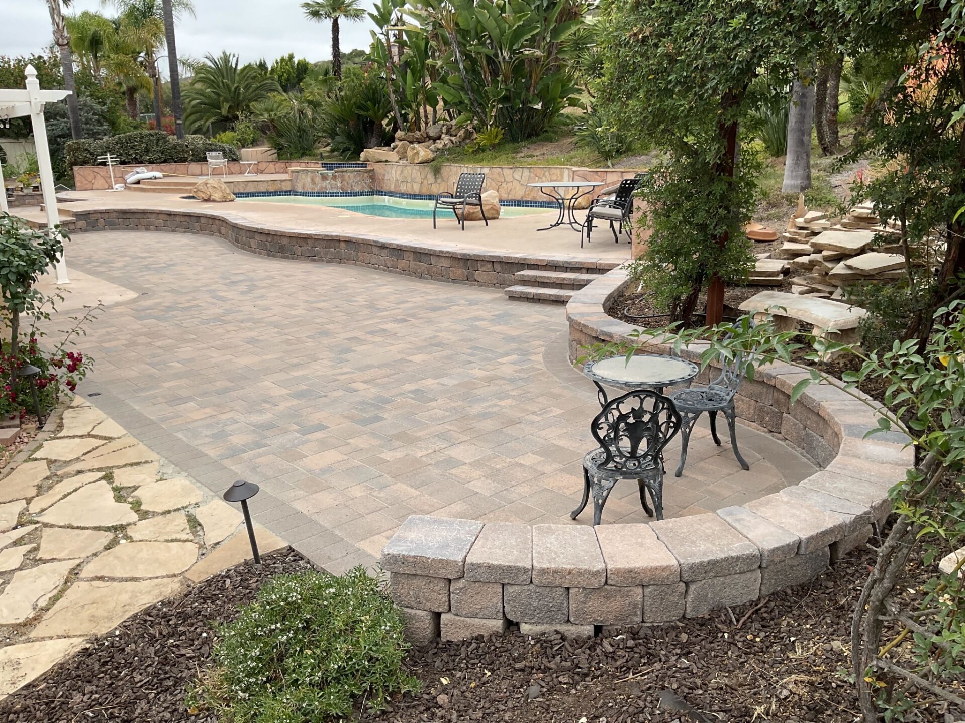 Paver patio and curved seat wall below the pool deck, Poway 92064