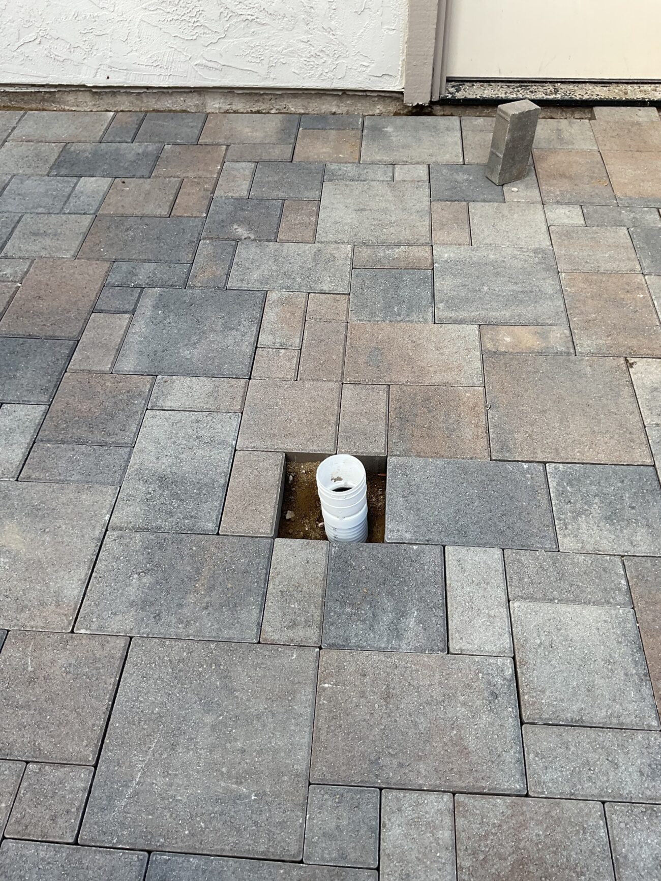 Drain piping rises through the in-progress ORCO Villa Express paver field before the opening is finished flush.