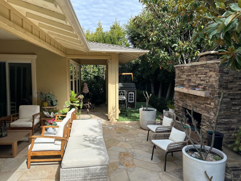 Completed residential backyard patio featuring natural stone flagstone pavers and a built-in stacked-stone fireplace...