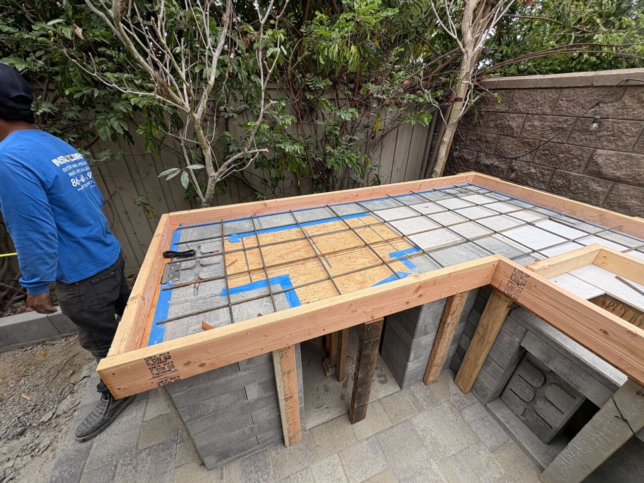 Backyard construction photo showing a masonry base for an outdoor kitchen/island built from concrete block with temporary...