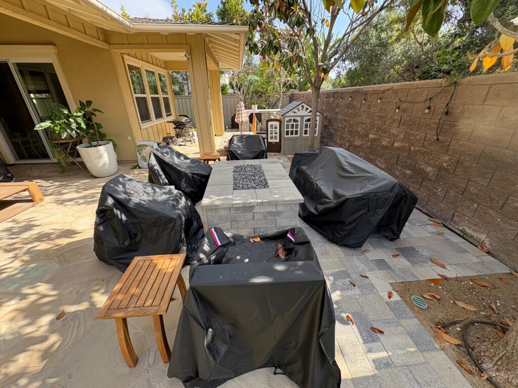 Finished interlocking paver patio with a square raised fire pit filled with lava rock at the center. Covered patio...