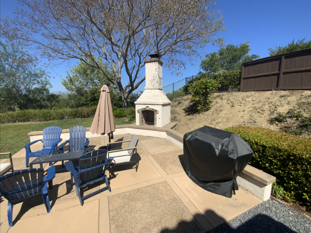 Finished interlocking paver patio with a built-in outdoor fireplace and low seat/retaining wall. Covered grill and...