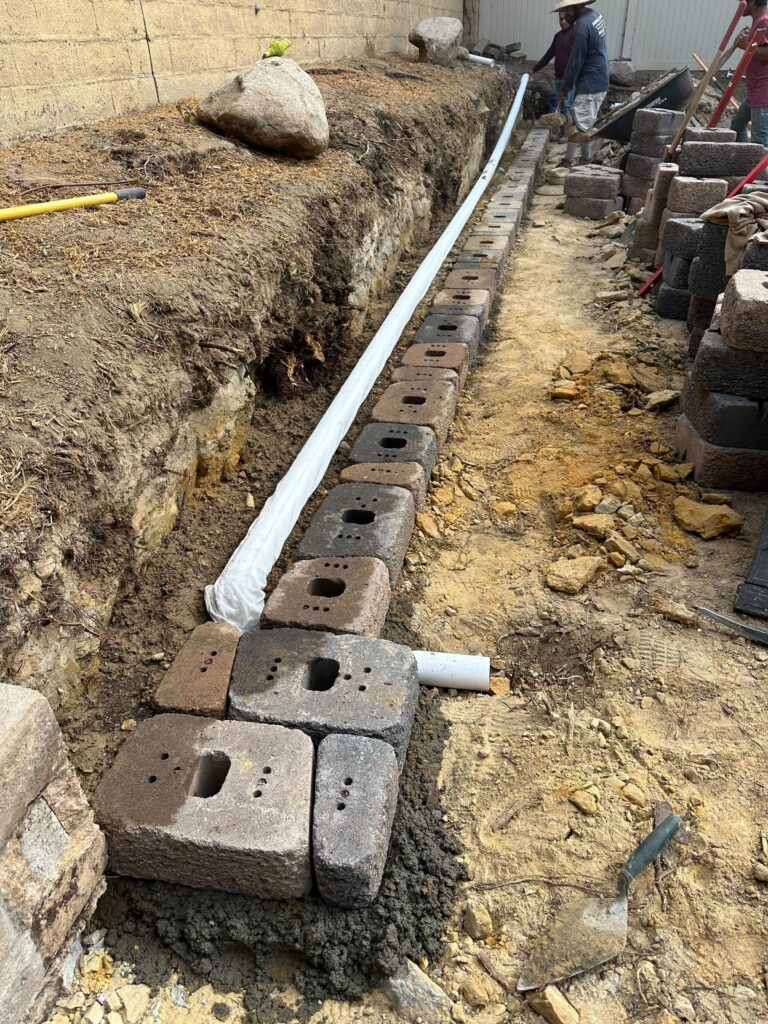Trench for a segmental retaining wall with a wrapped perforated drain pipe (French drain) installed on the trench bottom....