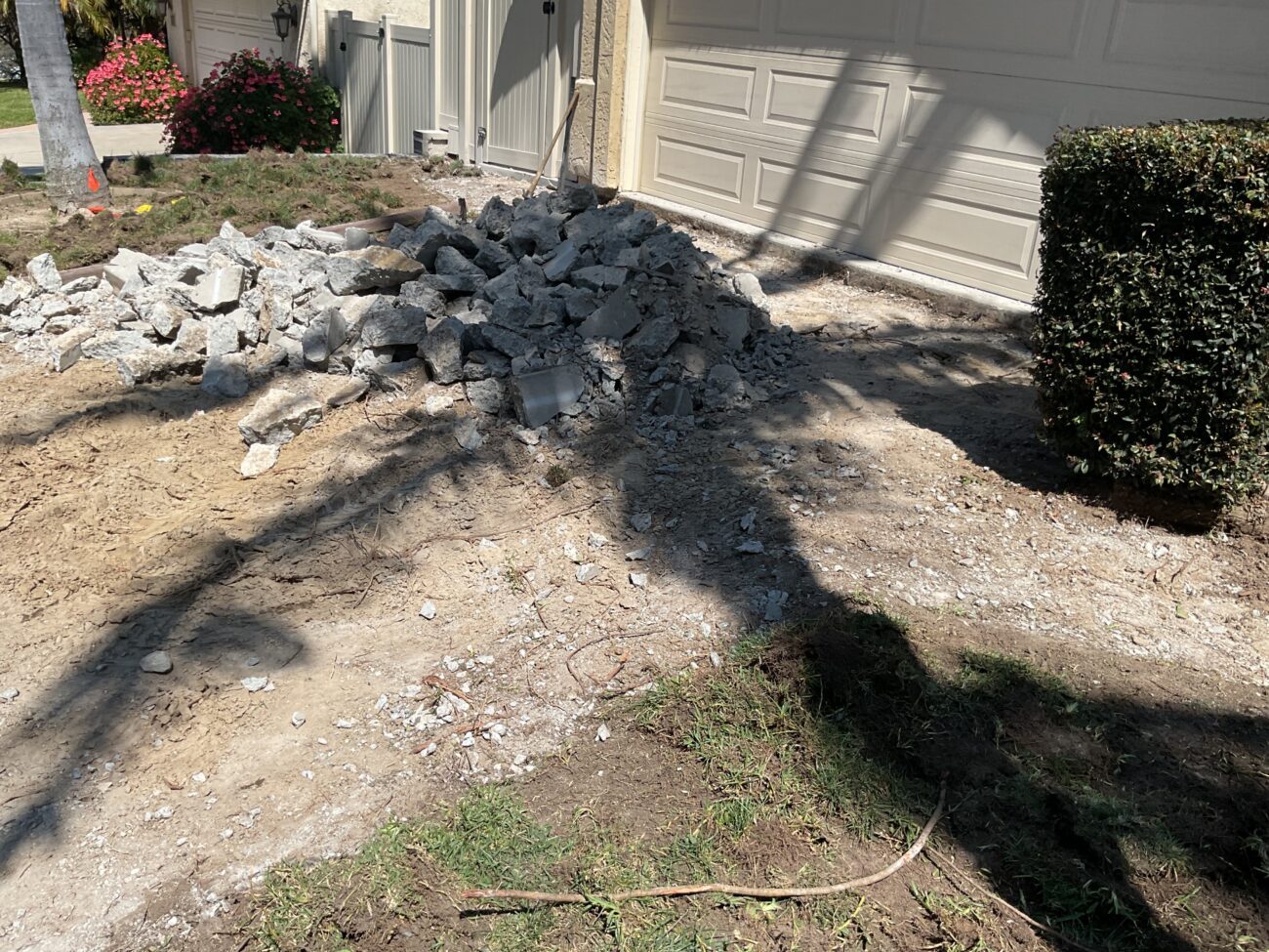 Front driveway area at a residential property showing demolished concrete broken into a pile of rubble next to the...