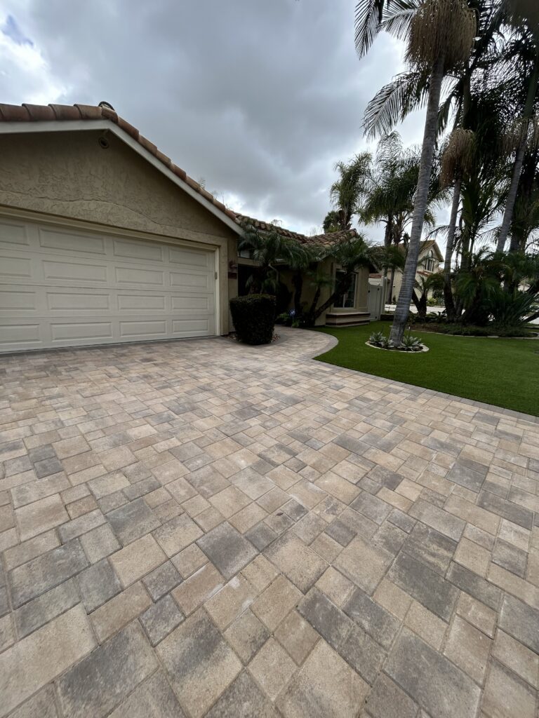 Completed interlocking paver driveway and adjoining paver patio at a residential front yard, with a neat curved edge of...