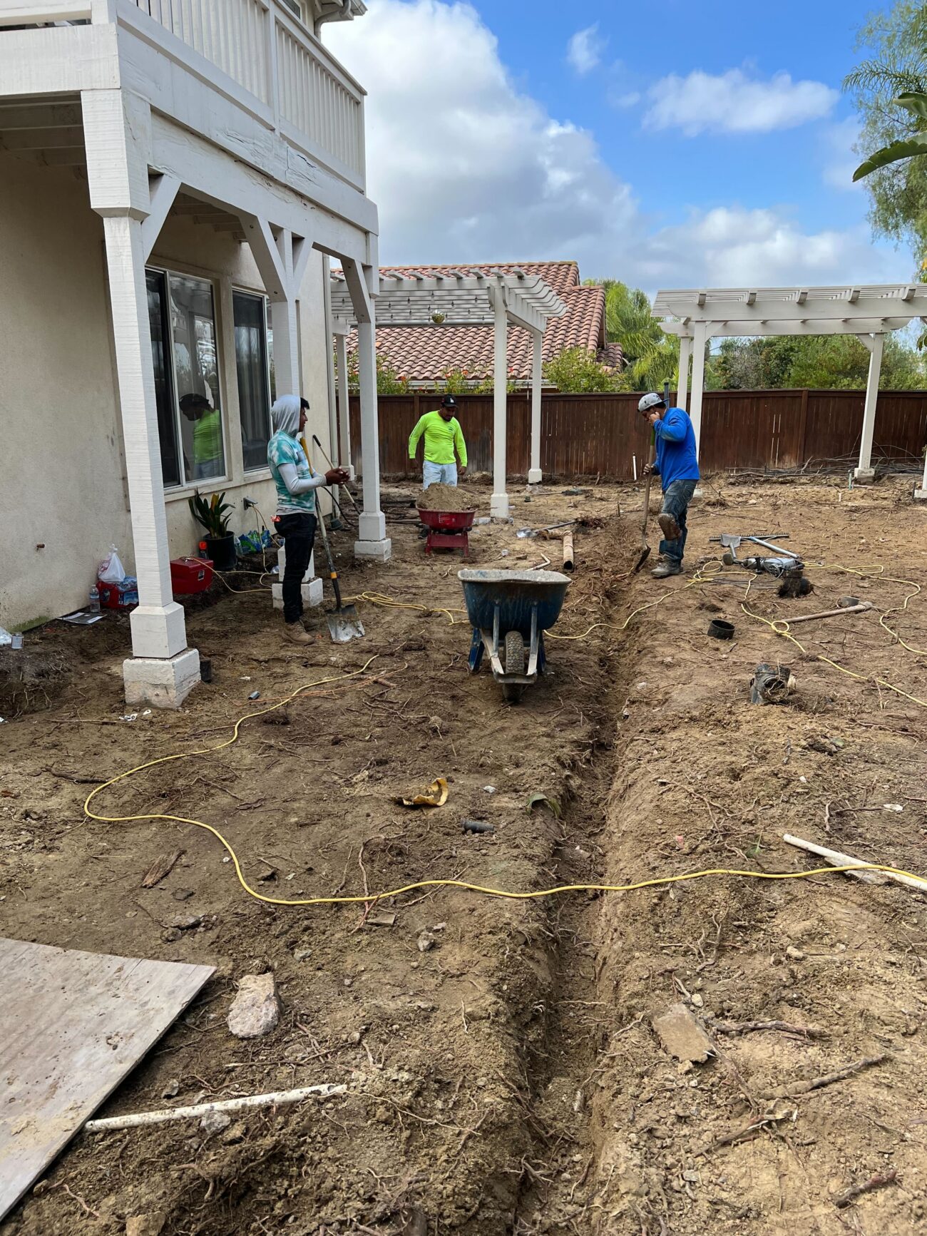 Backyard excavation showing a trimmed trench and exposed subgrade as crew prepare the area for a paver patio and drainage...