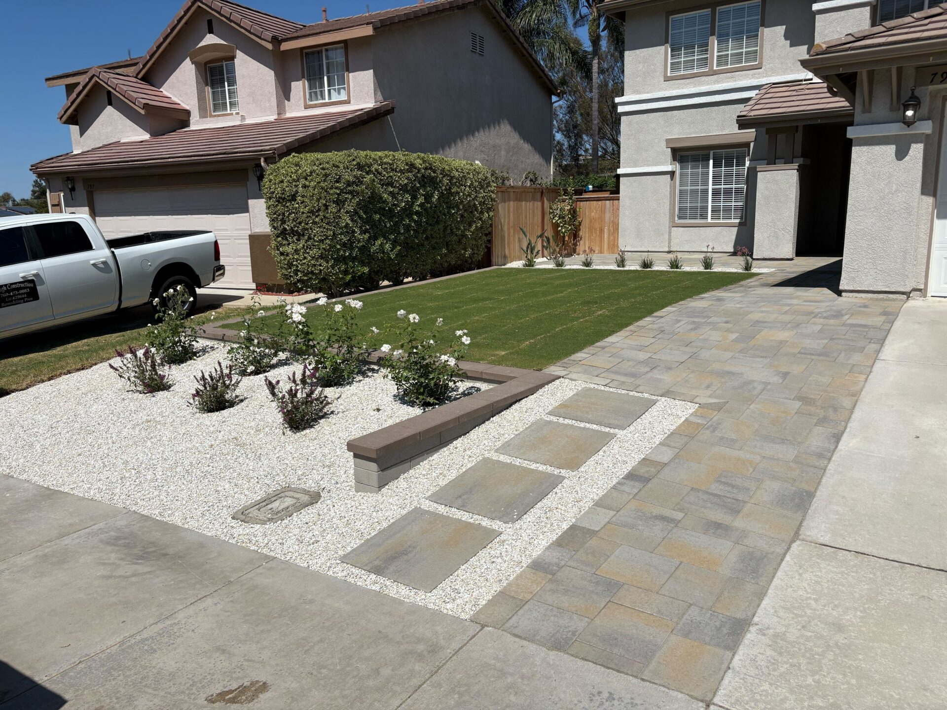 Finished front-yard installation showing interlocking paver driveway and walkway transitioning to a paved entry with adjacent artificial turf lawn. San Marcos project by Install It Direct.