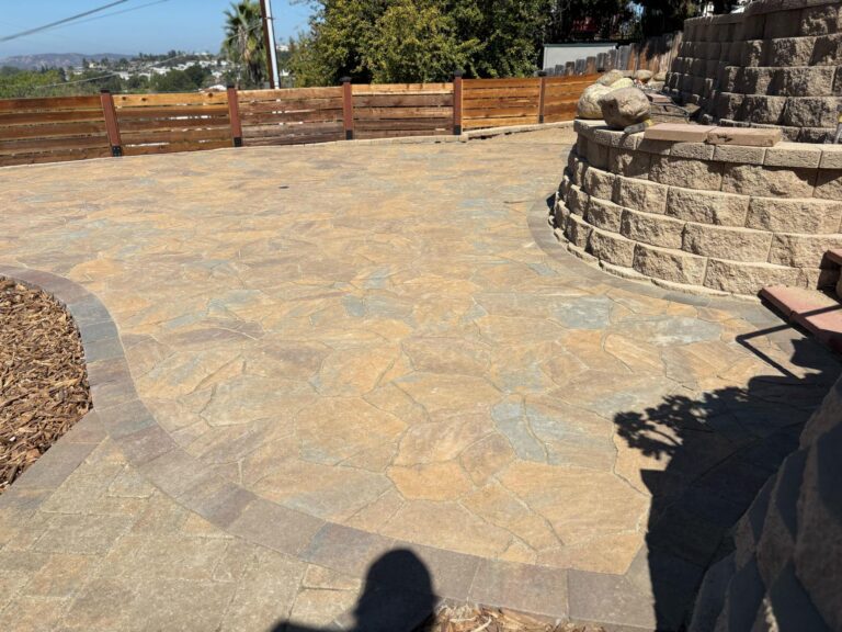 Finished residential paver patio in a flagstone/interlocking pattern with a contrasting soldier-course border. A...