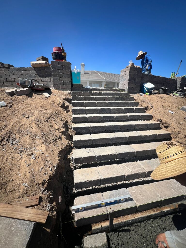 Residential backyard stair installation showing a run of interlocking paver steps up a graded slope with segmental...