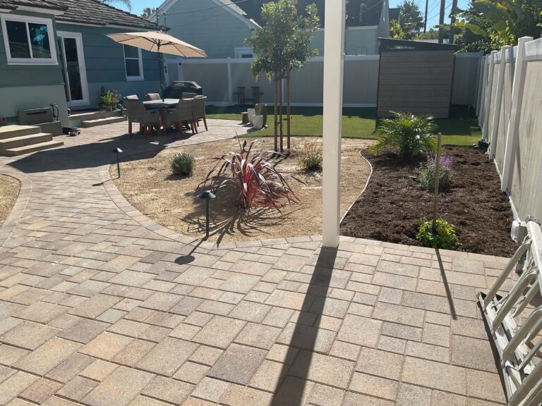 Backyard showing an installed interlocking paver patio and curved paver walkway leading to a dining/seating area. Mulched...