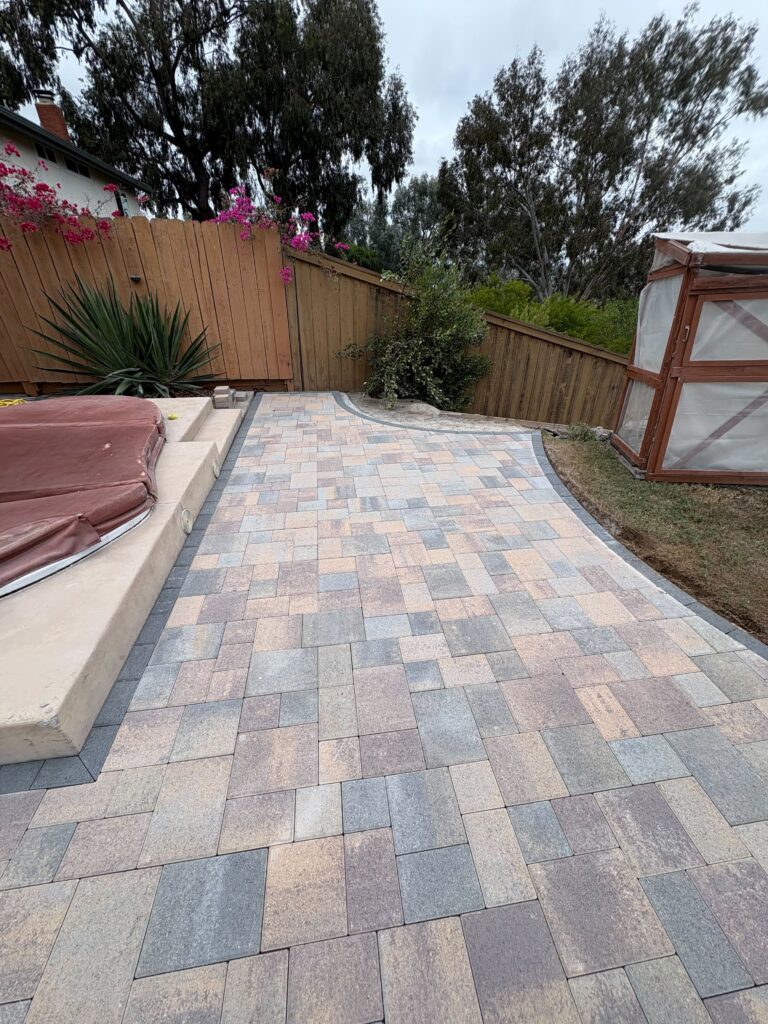 Finished interlocking concrete paver patio and walkway with a darker contrasting border and integrated concrete step/seat...