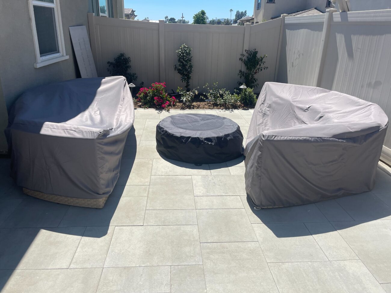 Finished backyard patio surfaced with large-format concrete pavers laid in a modular pattern, featuring a covered round...