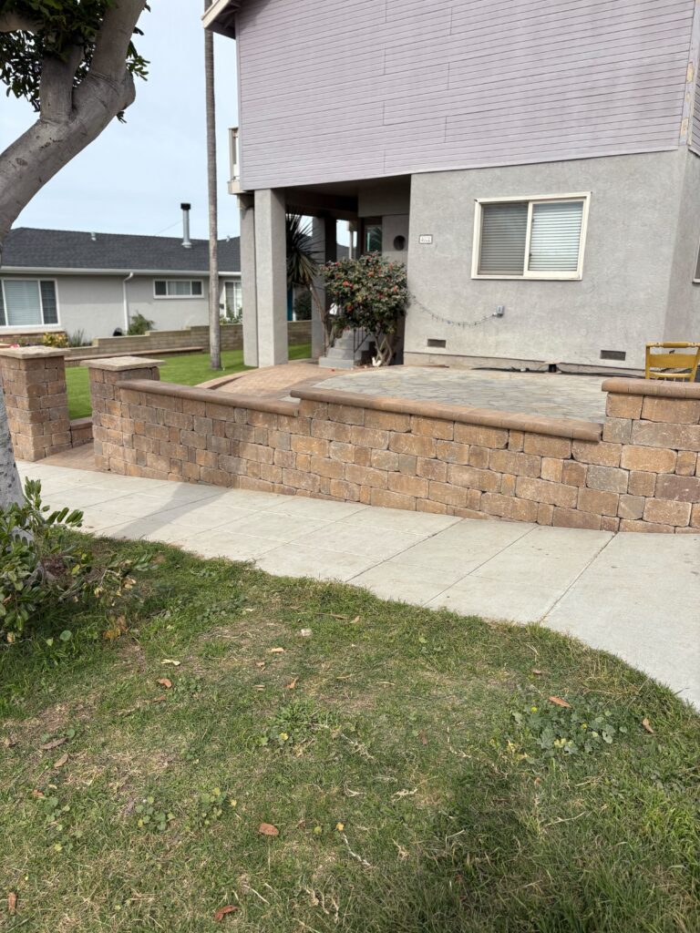 Segmental retaining wall and low seat wall constructed with interlocking pavers and capstones forming a raised...