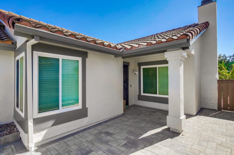 Covered front entry with stucco columns and an Angelus paver floor under the tile-roof porch.