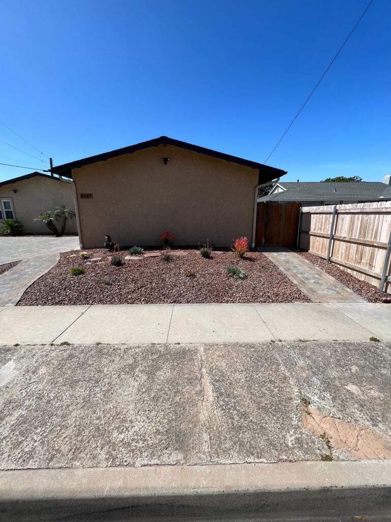 Front yard residential landscape showing a completed xeriscape with crushed stone mulch and drought-tolerant plantings....