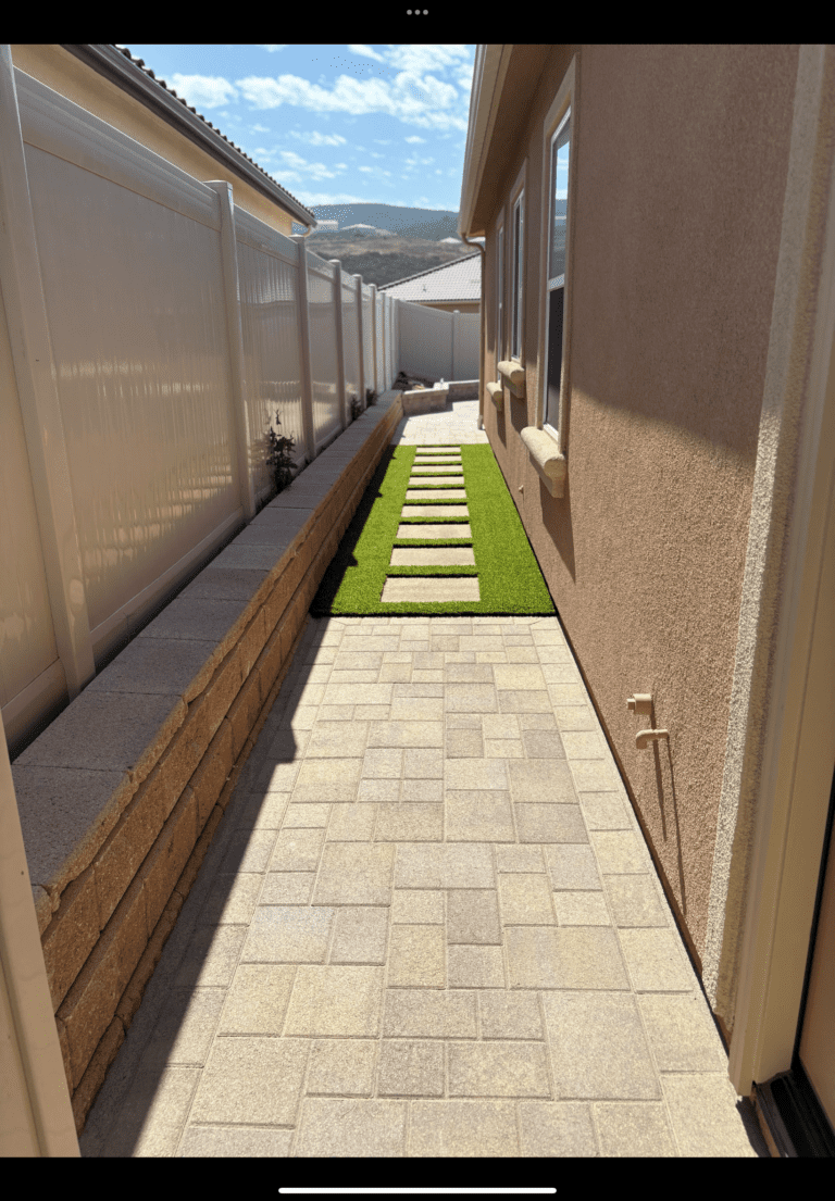 Finished interlocking paver walkway installed in a narrow side yard with clean joints and consistent pattern. A strip of...