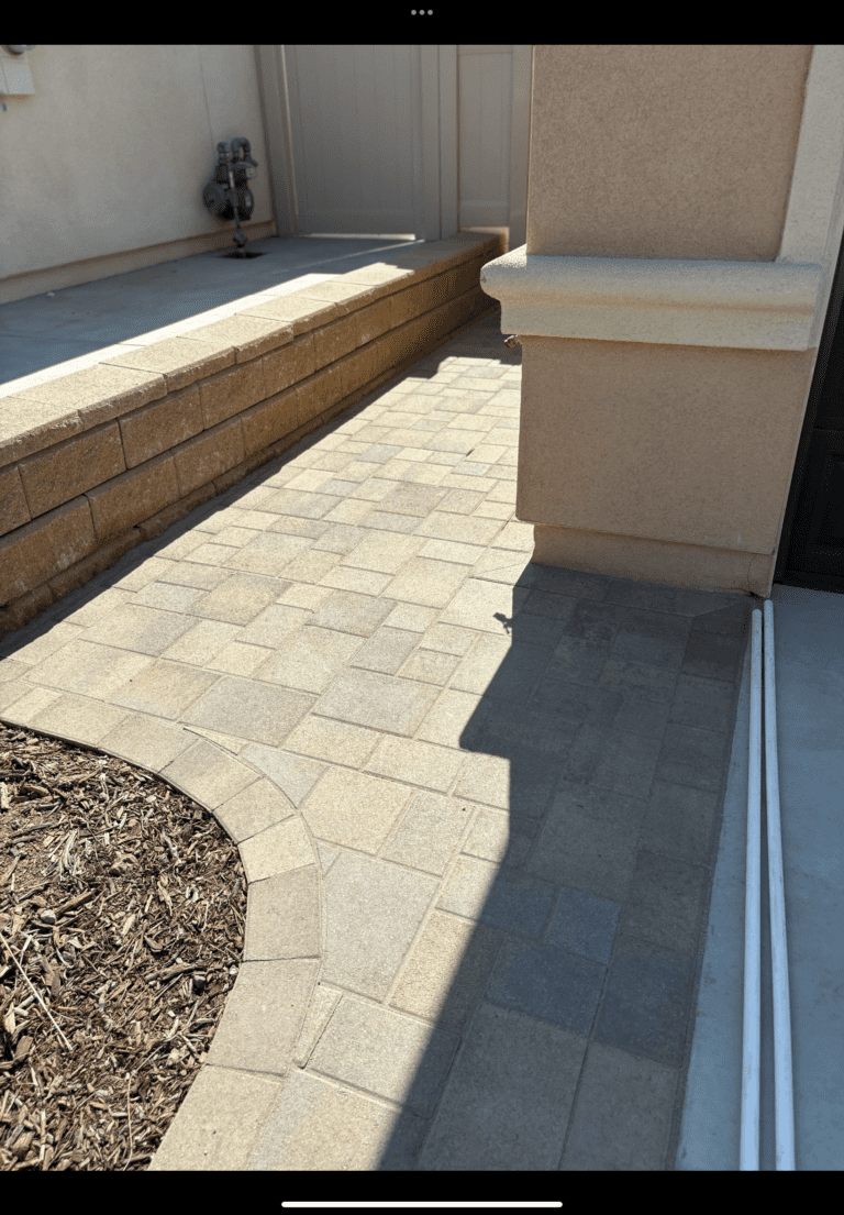 Completed paver walkway and adjoining segmental retaining wall with a soldier-course edge and curved paver banding next...