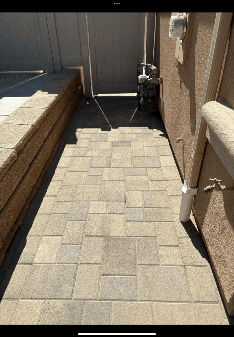 Narrow side-yard paved walkway installed with interlocking concrete pavers in an ashlar-like pattern between a segmental retaining wall and the home's stucco exterior. San Marcos project by Install It Direct.