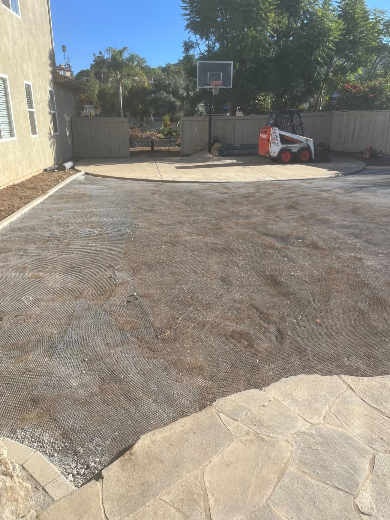 Base fabric and aggregate prep underway across the front-yard work area.
