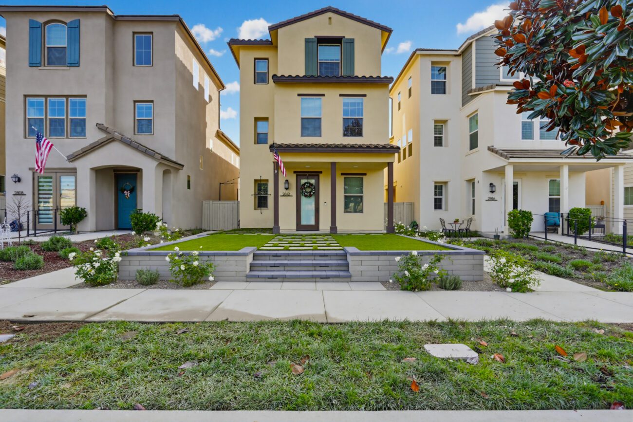 Wide front elevation with the terraced entry and lawn grid.