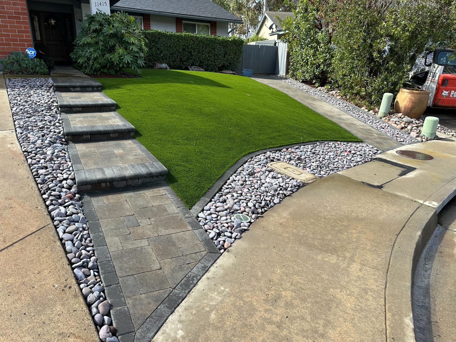 Finished front-yard hardscape showing interlocking paver walkway and stepped paver treads leading to the house....