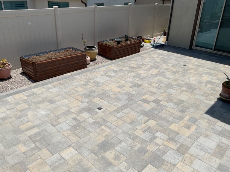 Finished interlocking concrete pavers installed in a mixed-size pattern form a clean residential patio with a central...