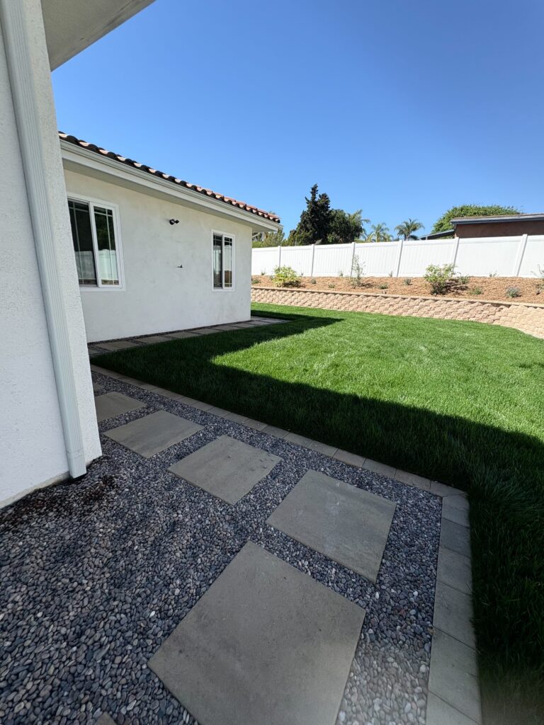 Concrete paver stepping stones in pebble aggregate next to newly sodded Bermuda lawn and segmental retaining wall in Vista, CA. Install It Direct project.