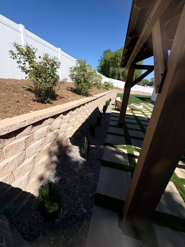 Segmental retaining wall along planted slope with stepping-stone paver walkway in artificial-turf strips and pergola in Vista, CA. Install It Direct project.
