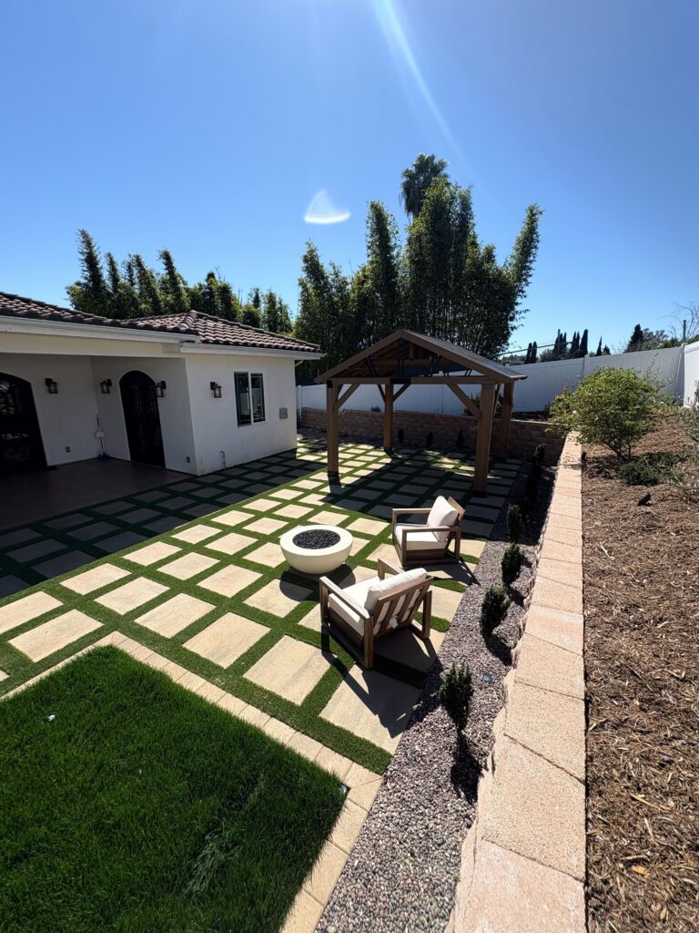 Round fire feature and seating on the paver grid with pergola, segmental retaining wall, and raised planting bed in Vista, CA. Install It Direct project.