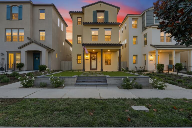 Front elevation of a finished residential landscape showing a stepped paver entry with large square pavers set in artificial turf and low segmented retaining walls forming raised planters. Escondido project by Install It Direct.