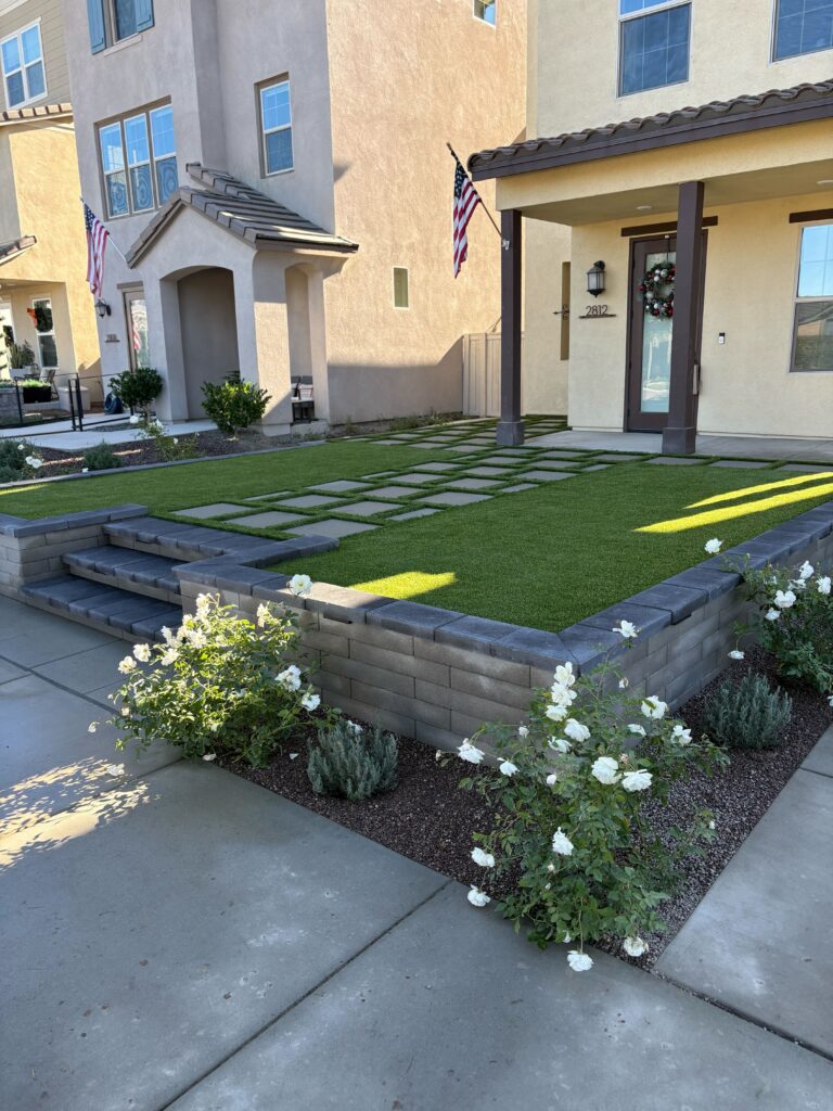 Front yard shows a completed residential hardscape with synthetic turf and large square pavers set as stepping stones. Escondido project by Install It Direct.