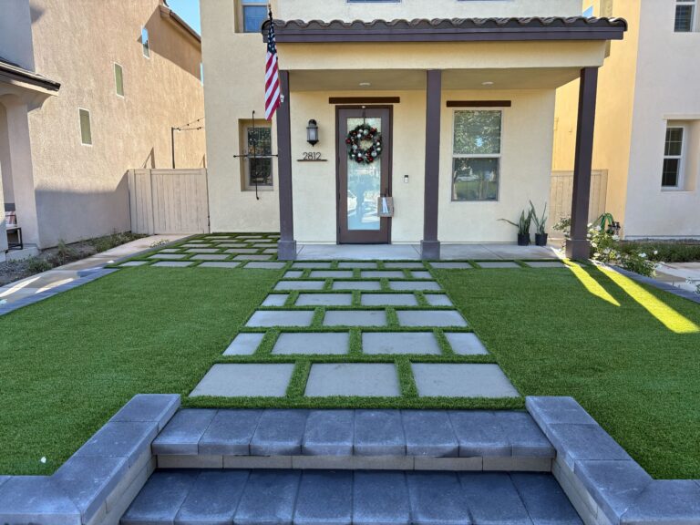 Finished residential front-yard landscape featuring rectangular concrete pavers set in a grid pattern with artificial turf infill forming a walkway to a covered front porch. Escondido project by Install It Direct.
