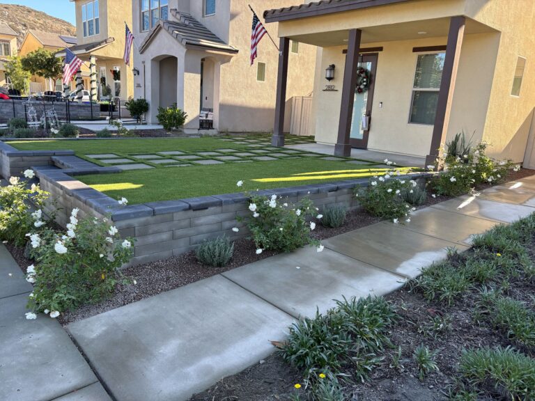 Front yard shows a completed low segmental retaining wall with capstone surrounding an artificial turf lawn. Escondido project by Install It Direct.