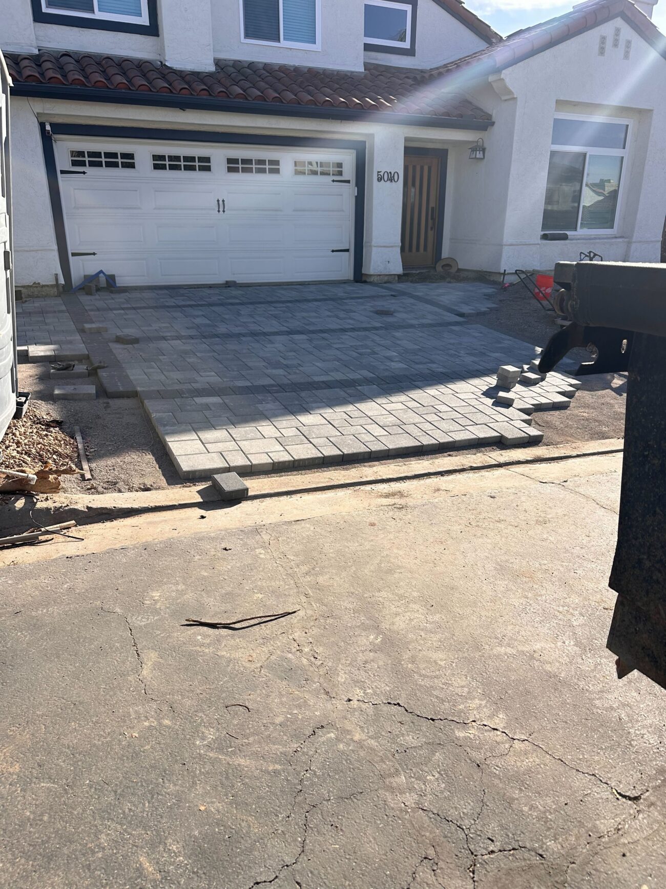 Front driveway of a single-family home where interlocking pavers are being installed. Majority of the paver field is laid...