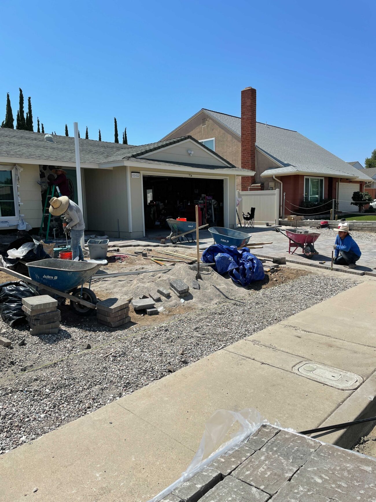 Residential front-yard paver installation underway. Crews are preparing the gravel base and staging interlocking pavers,...