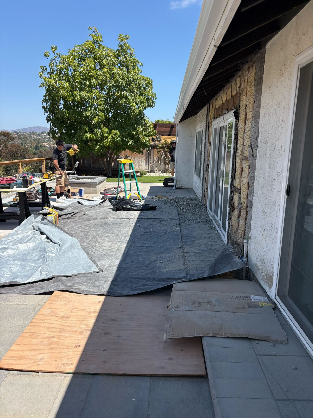 Protective tarps and temporary ramps go in as the backyard is opened for site prep.