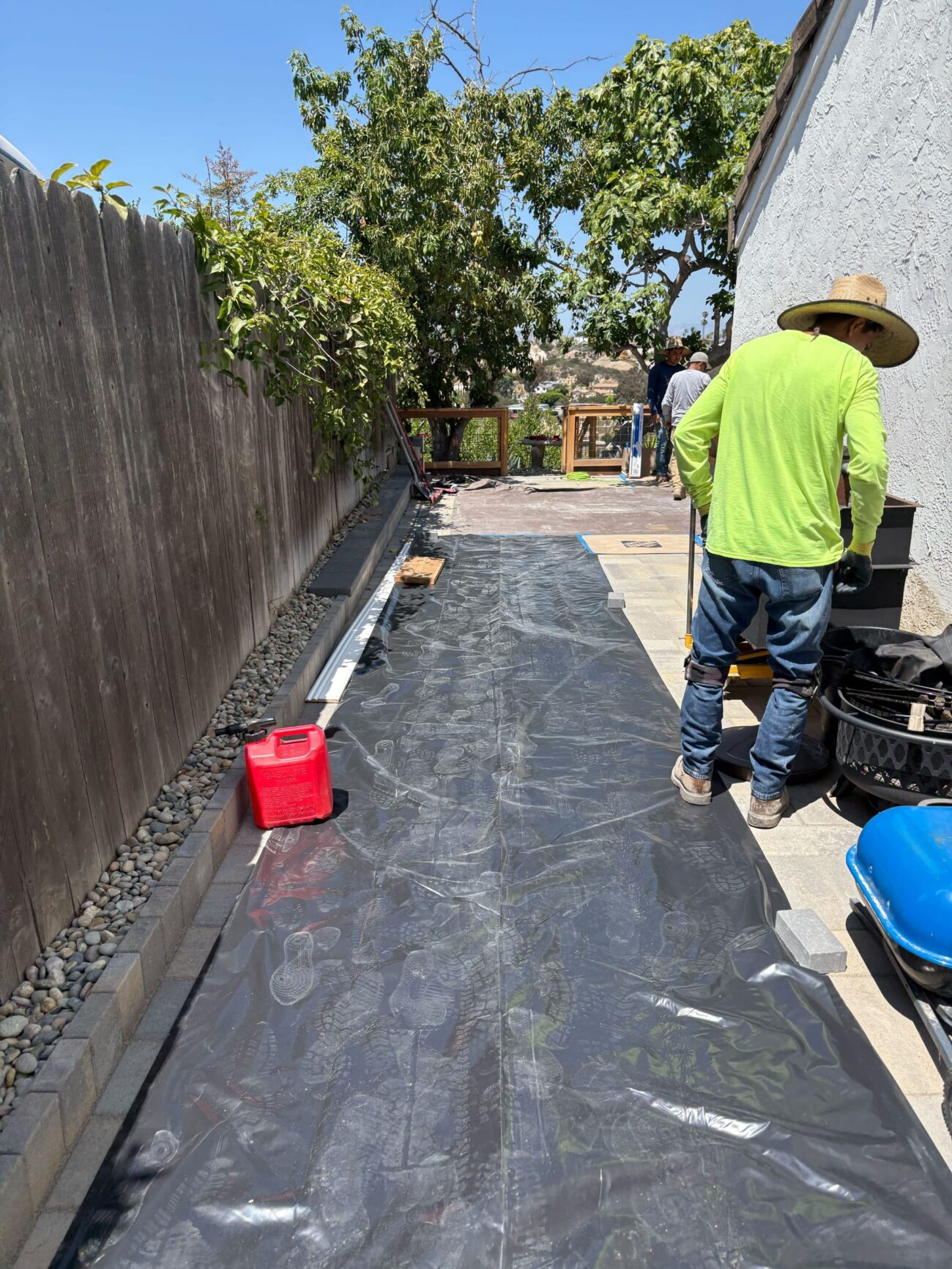 Landscape fabric and drainage gravel are set along the side-yard run before the paver finish.