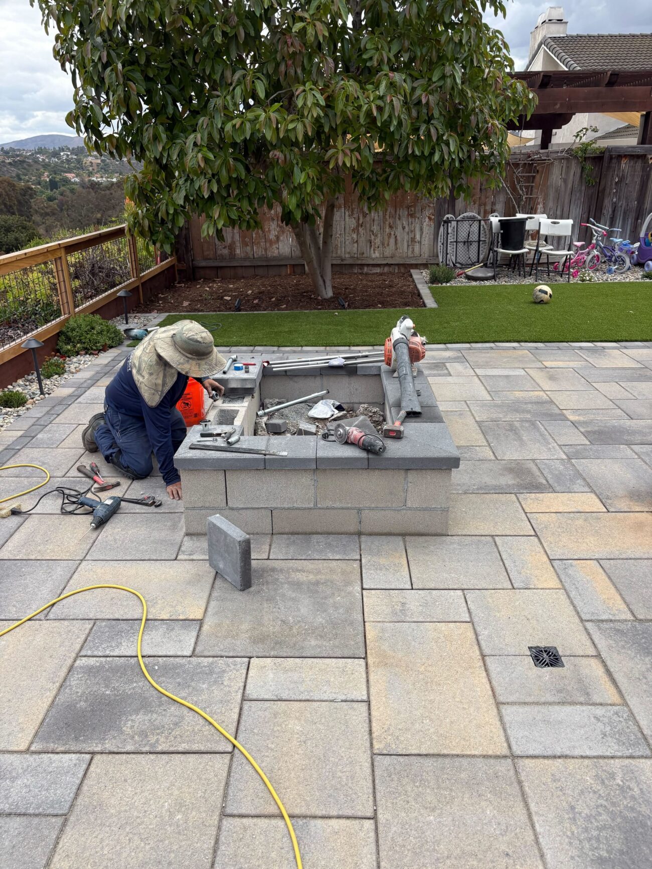 A crew member cuts and sets the wall surround into the new paver field.