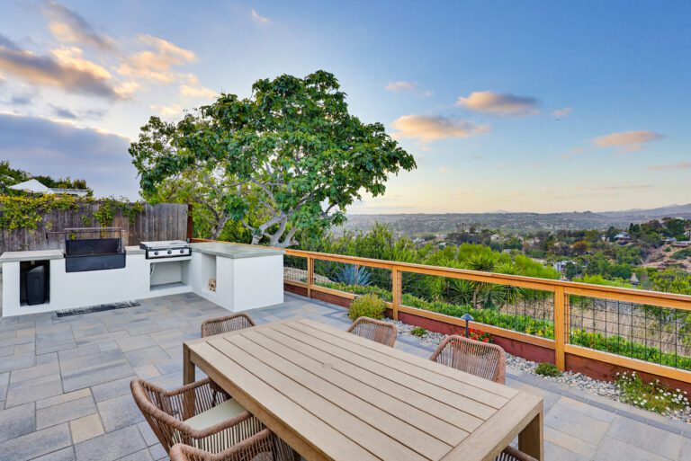 Stucco BBQ island with concrete counter anchors the terrace at golden hour